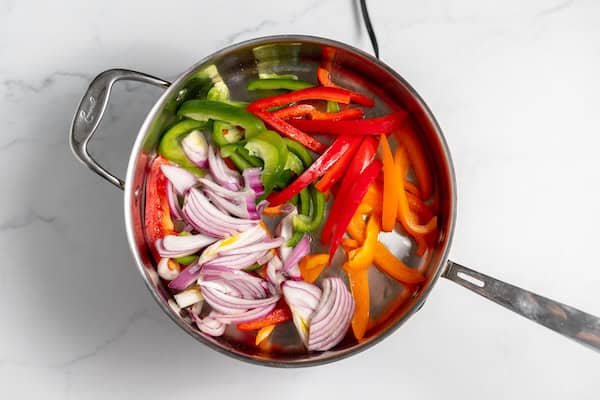 Image, taken from above, shows bell peppers and onions being sauteed for chicken scampi