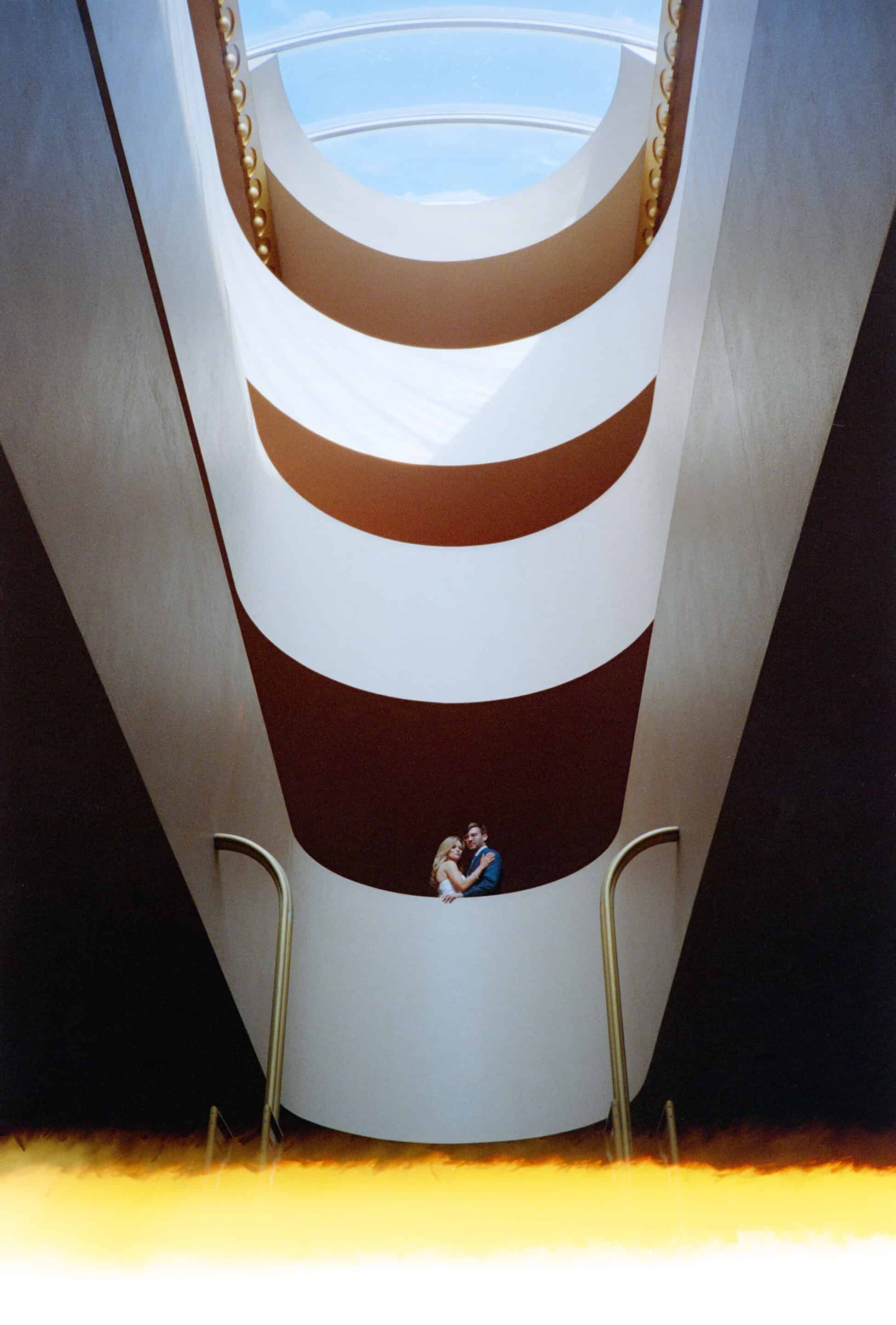 Modern architectural interior with spiral staircase and skylight ceiling.