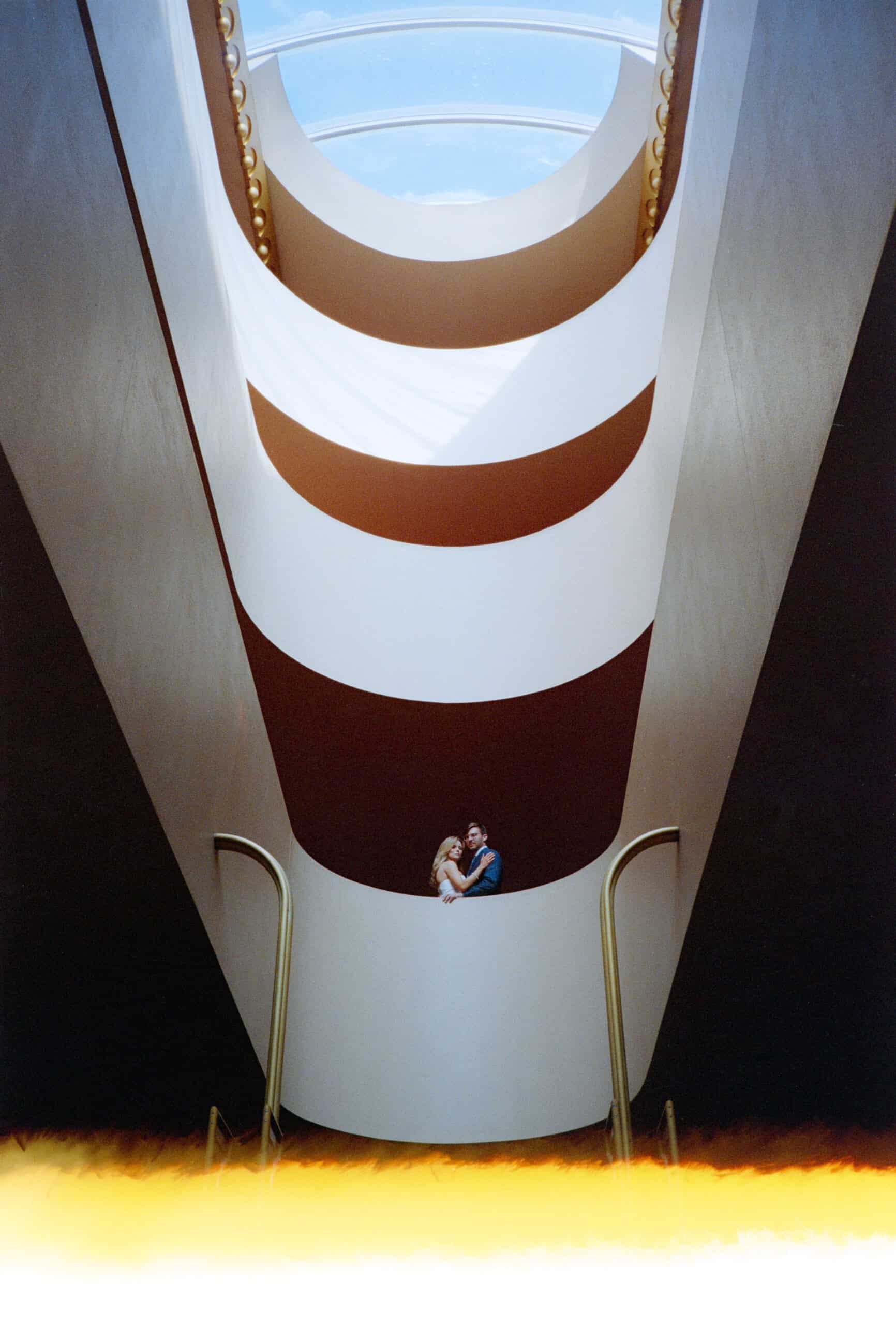 Modern architectural interior with spiral staircase and skylight ceiling.