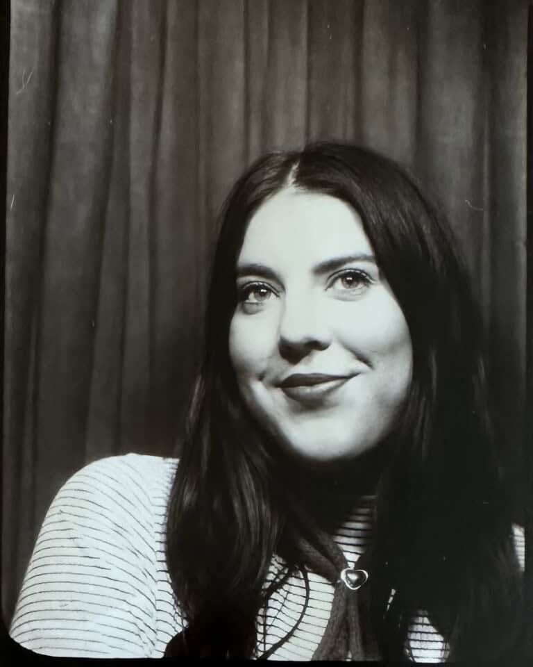 Portrait of a woman with dark hair and a striped shirt in black and white.