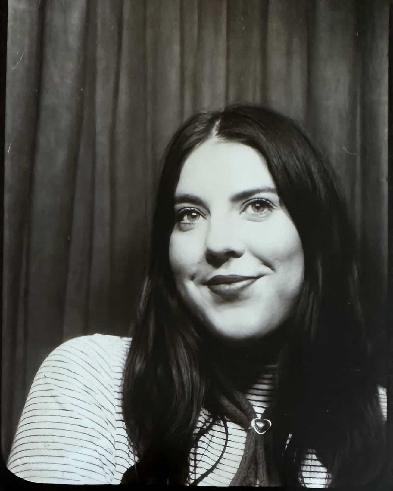 Portrait of a woman with dark hair and a striped shirt in black and white.