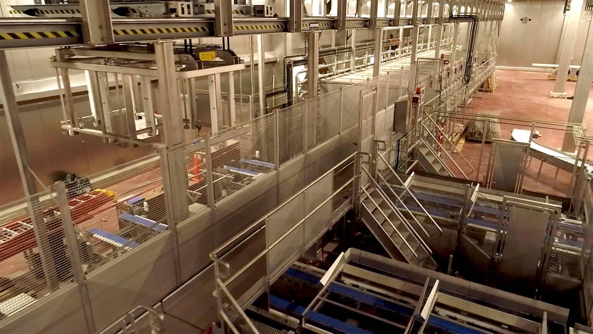 A view down on a working area of the Ruprecht Meat Company Processing Facility is full of metal equipment, ladders, and gridded walkways on a red concrete floor. Keeley Construction was responsible for the expansion and new construction.