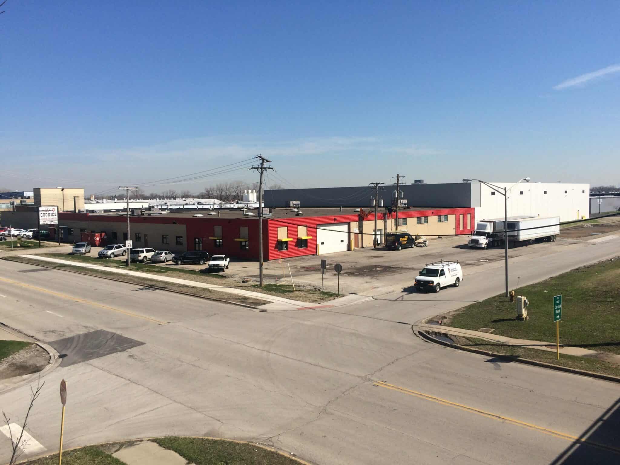 The finished red and white Pure’s Food building, completed by Keeley Construction, Inc., sits on the corner of a block. A couple of cars and a truck are occupying the streets surrounding the facility.