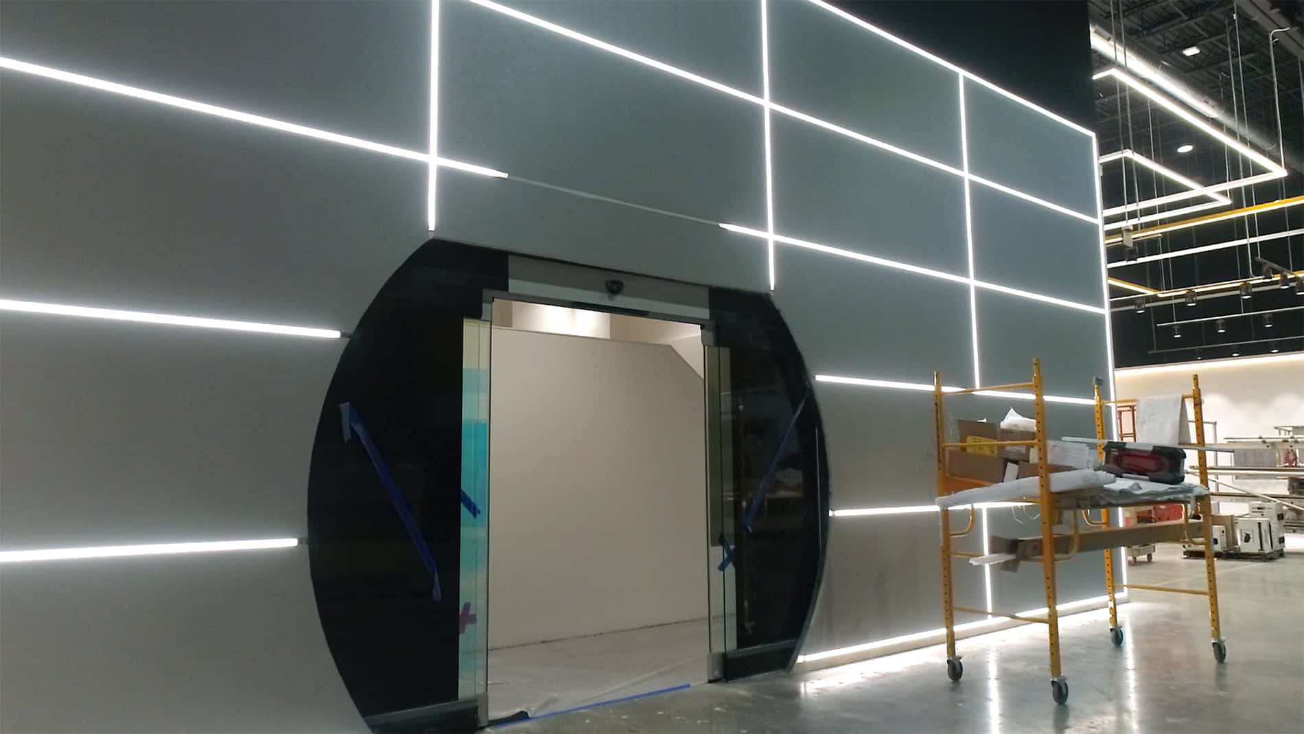 A wall with lights running vertical and horizontal with a large circular doorway in the middle.