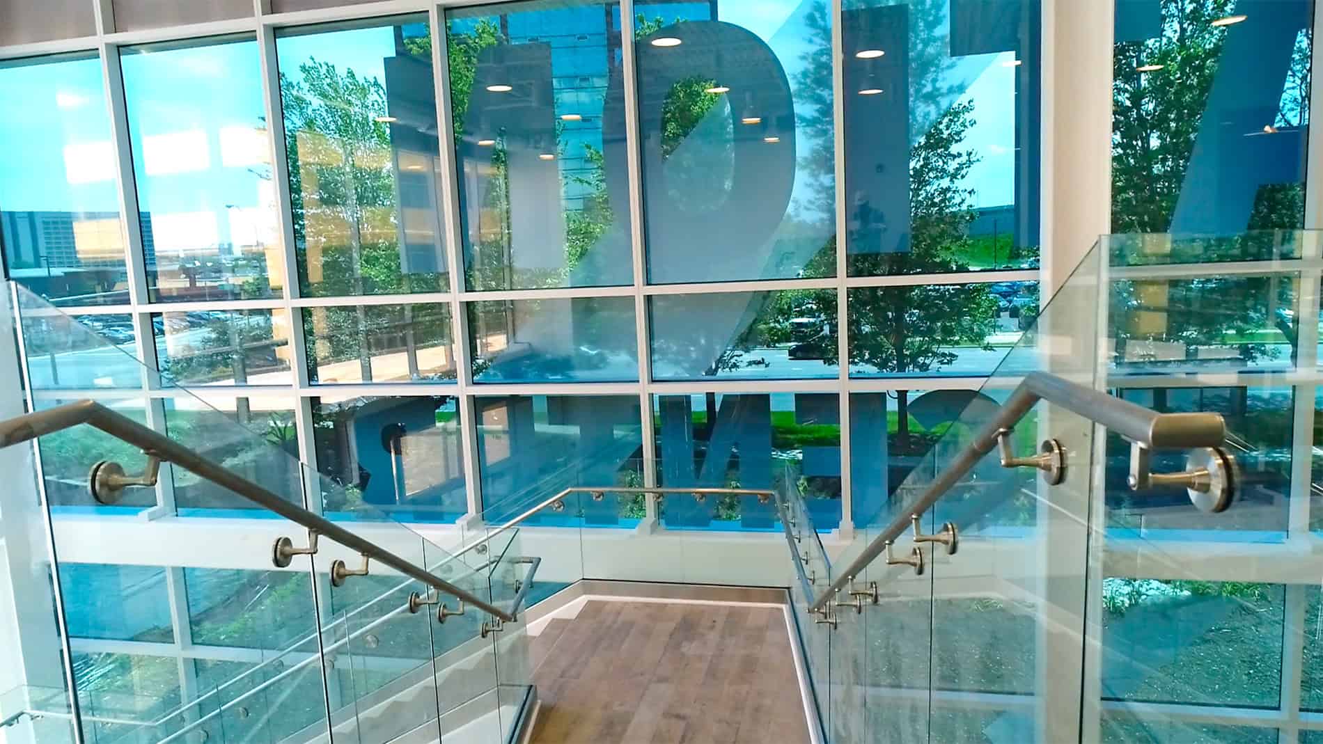 A glass wall with large letters in each window and a staircase in front.