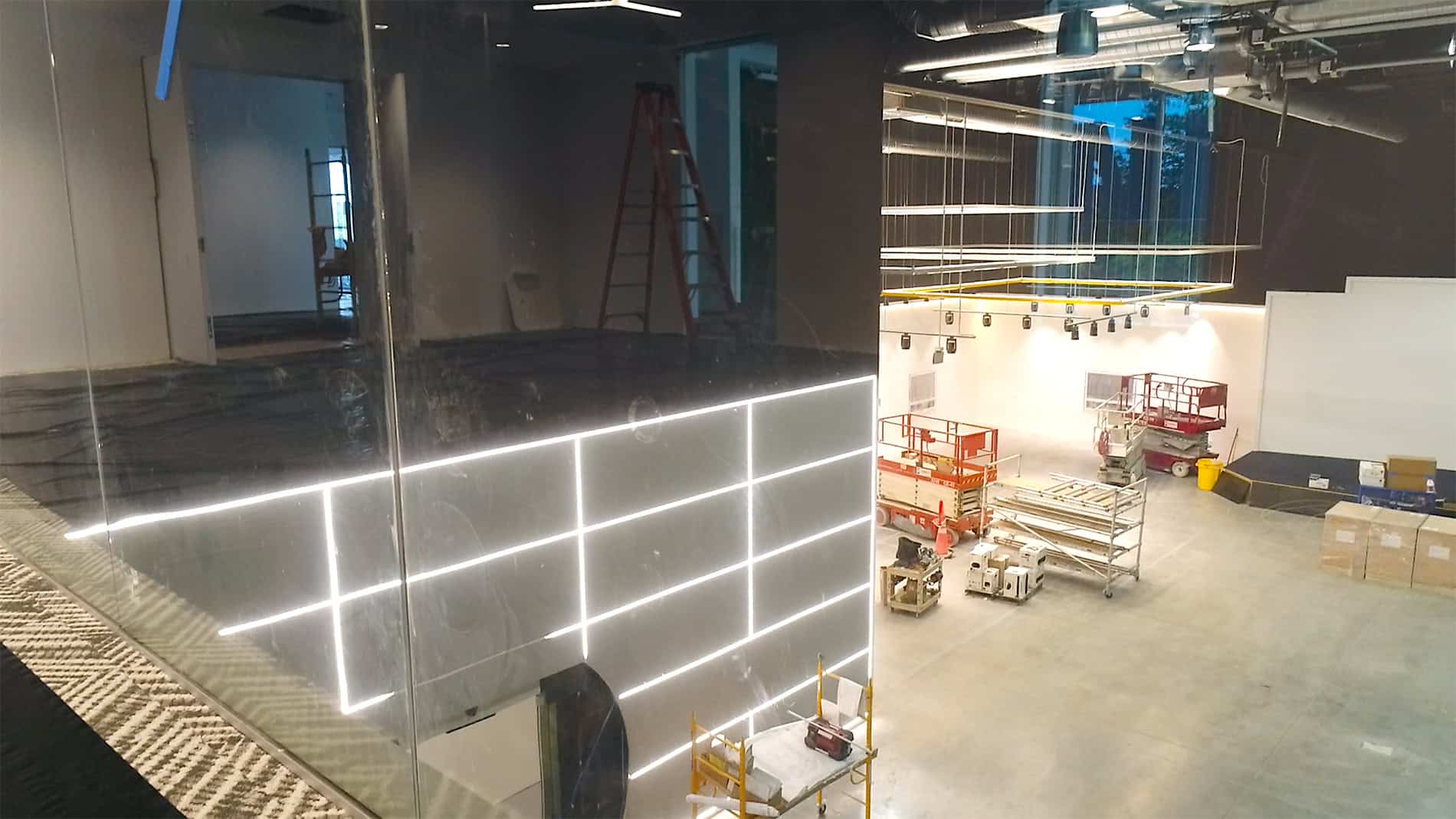 Looking down into a large unfinished room with black and white walls and stacks of equipment and supplies to complete the DHL Americas Innovation Center.
