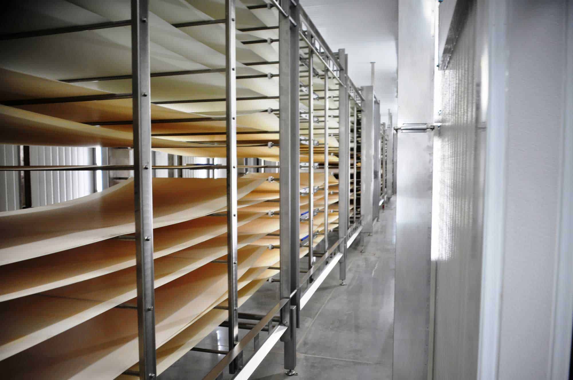 A clean, long stainless steel rack extends down the length of the interior of Grecian’s Delight cold storage and food processing facility.