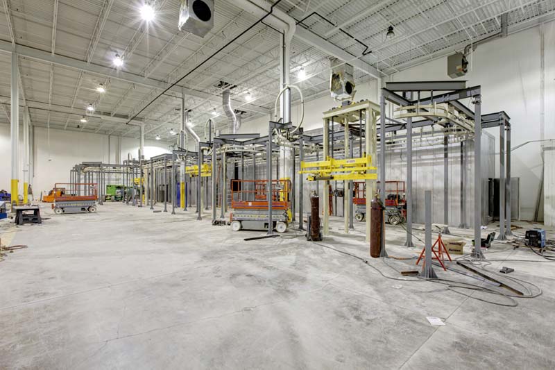 A large warehouse-like interior is empty except for construction equipment, supplies, and metal structures marking where new walls will be built. The Lenze project was completed by Keeley Construction, Inc.