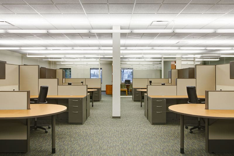 A view down the Lenze corporate interior with open workspaces on either side, including open cubicles with round tables at each station.