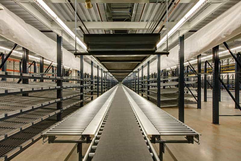 A view down the center of a long conveyor belt flanked by more industrial equipment. Keeley Construction built the facility based on the needs of their client, Wilton Industries.
