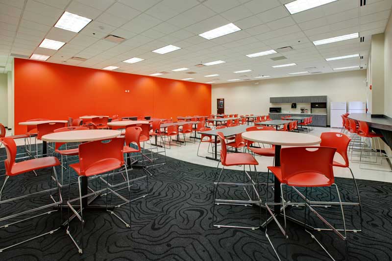 Keeley Construction built this new break room full of tables, chairs, and lights for Wilton Industries’ employees.