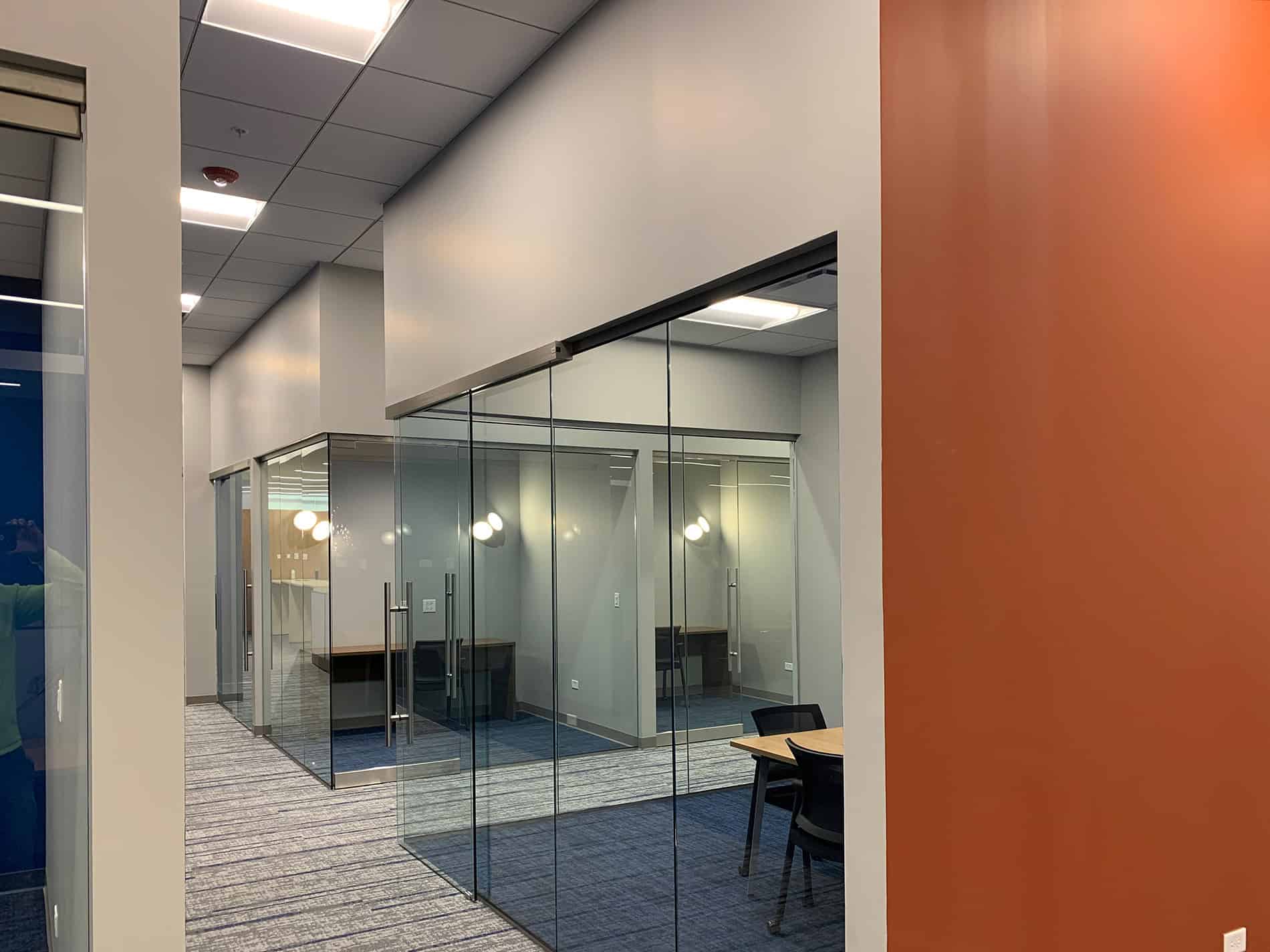 A hallway with walls of glass that separate office spaces. The CODA renovation project was completed by Keeley Construction, Inc.