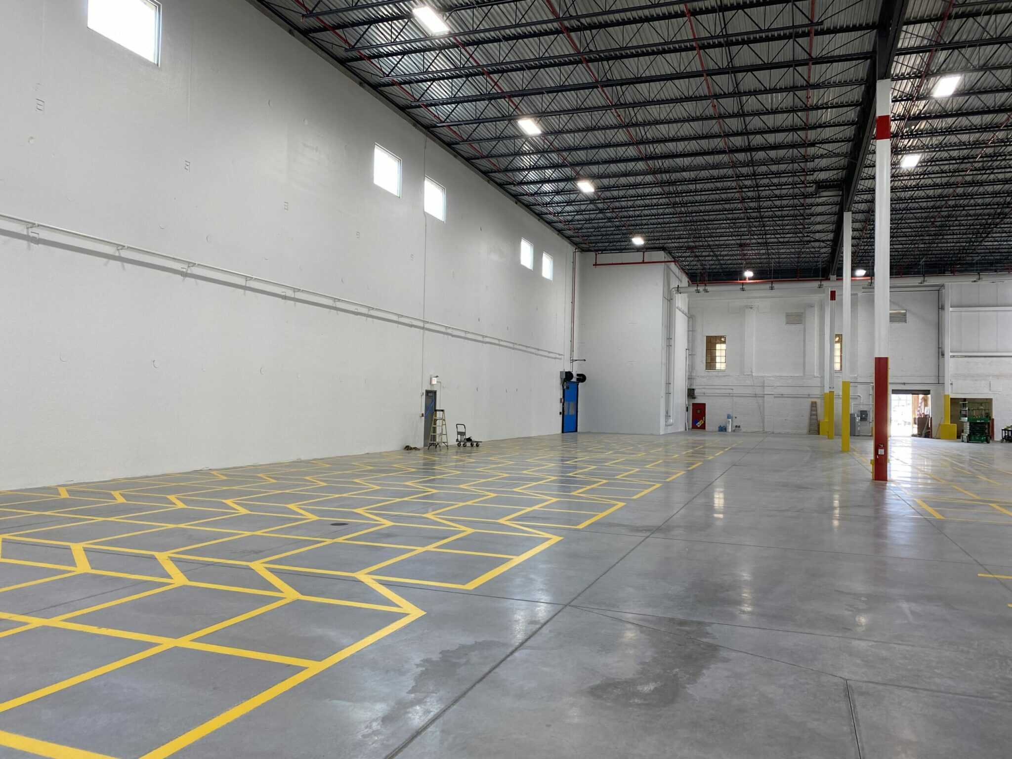 The Nalco Chemical building, built by Keeley Construction, Inc. contains this large warehouse space, complete with painted poles, yellow demarcation, and a ladder in the distance.