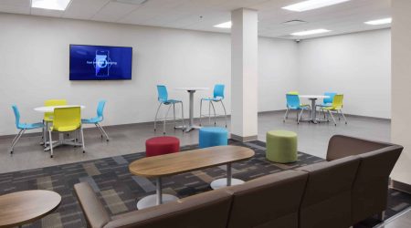 BCI Acrylic has a modern employee lounge with colorful plastic chairs, a brown couch and tables of varying heights.