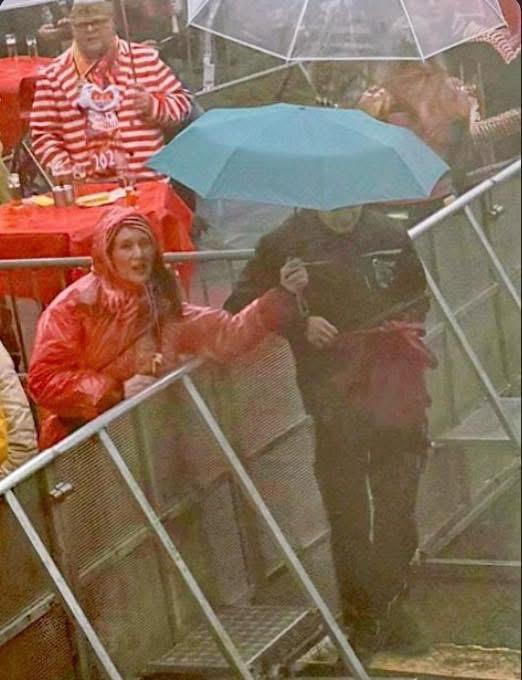 Bunte Karnevalsheldin bei Weiberfastnacht mit Regenschirm im Regen.