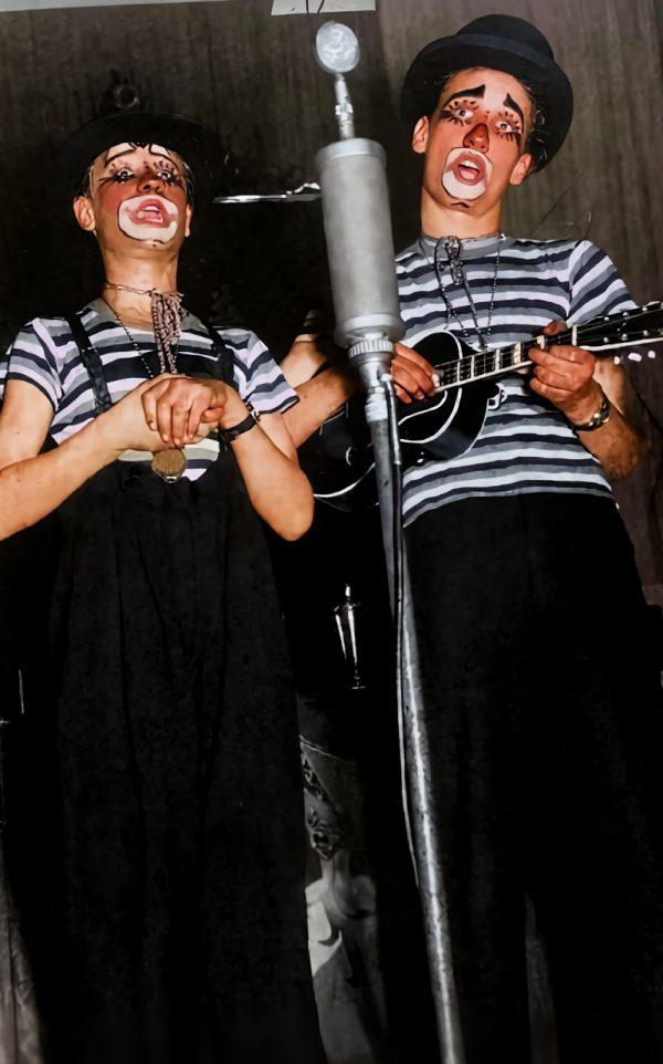 Zwei Karnevals-Künstler mit Make-up, Mikrofon und Gitarre bei der Performance.