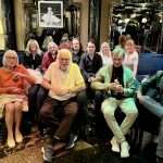Bunte Gruppe von Menschen sitzt in einem eleganten Raum, lachen und genießen den Moment.