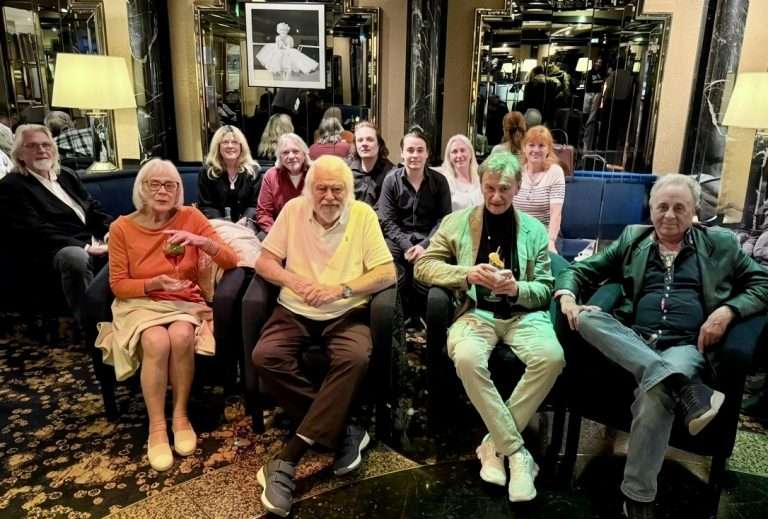 Bunte Gruppe von Menschen sitzt in einem eleganten Raum, lachen und genießen den Moment.