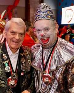 Zwei Karnevalisten in bunten Kostümen, einer als Clown, feiern beim Karneval.