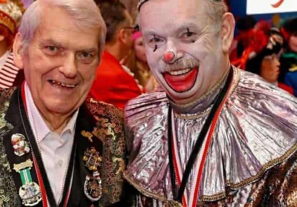 Zwei Karnevalisten in bunten Kostümen, einer als Clown, feiern beim Karneval.