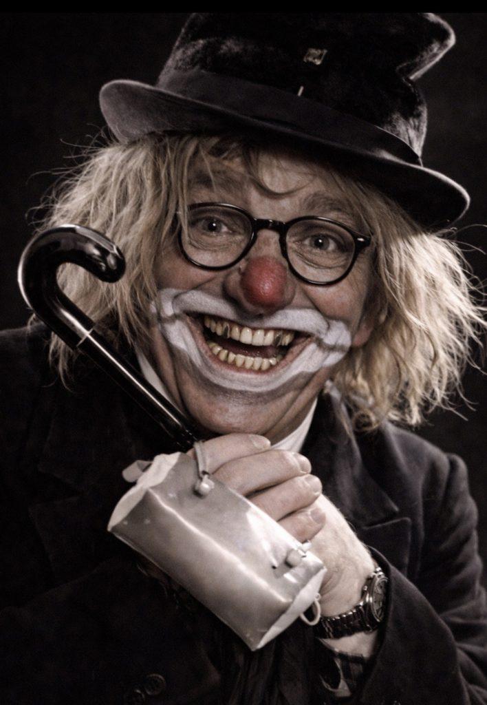 Fröhlicher Clown beim Kölner Karneval mit roter Nase und Lachen.