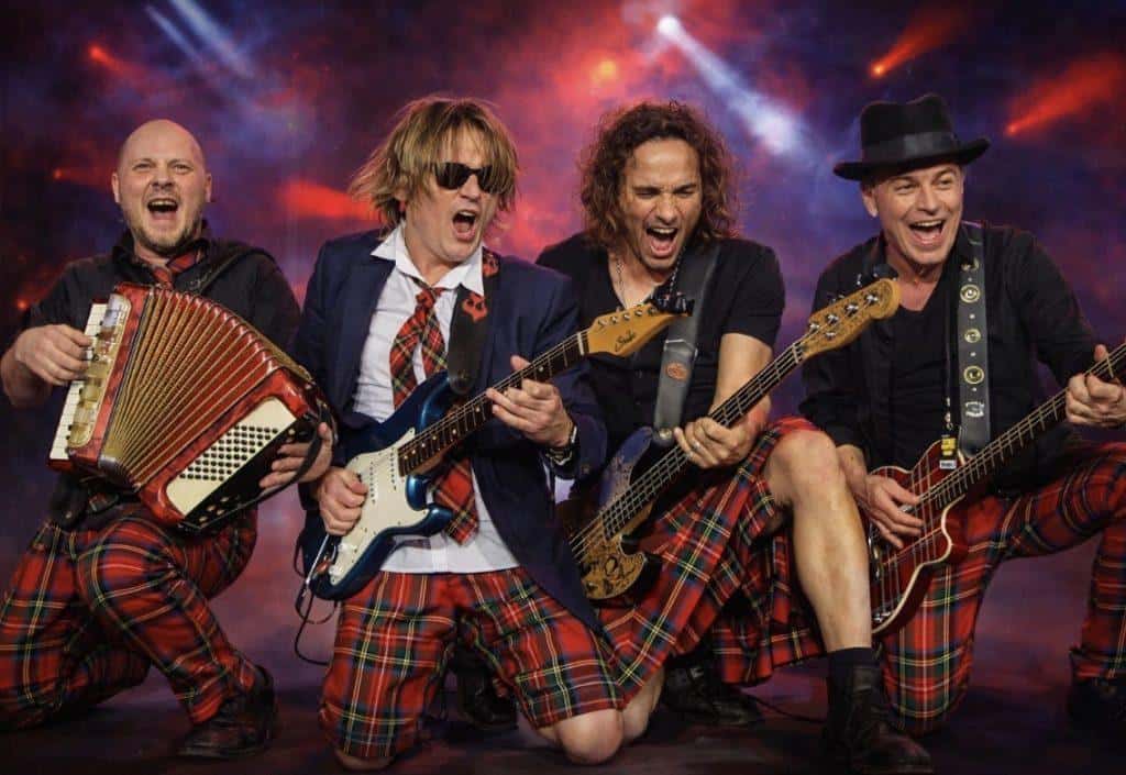 Bunte Musiker in Karnevalskostümen spielen auf der Bühne.