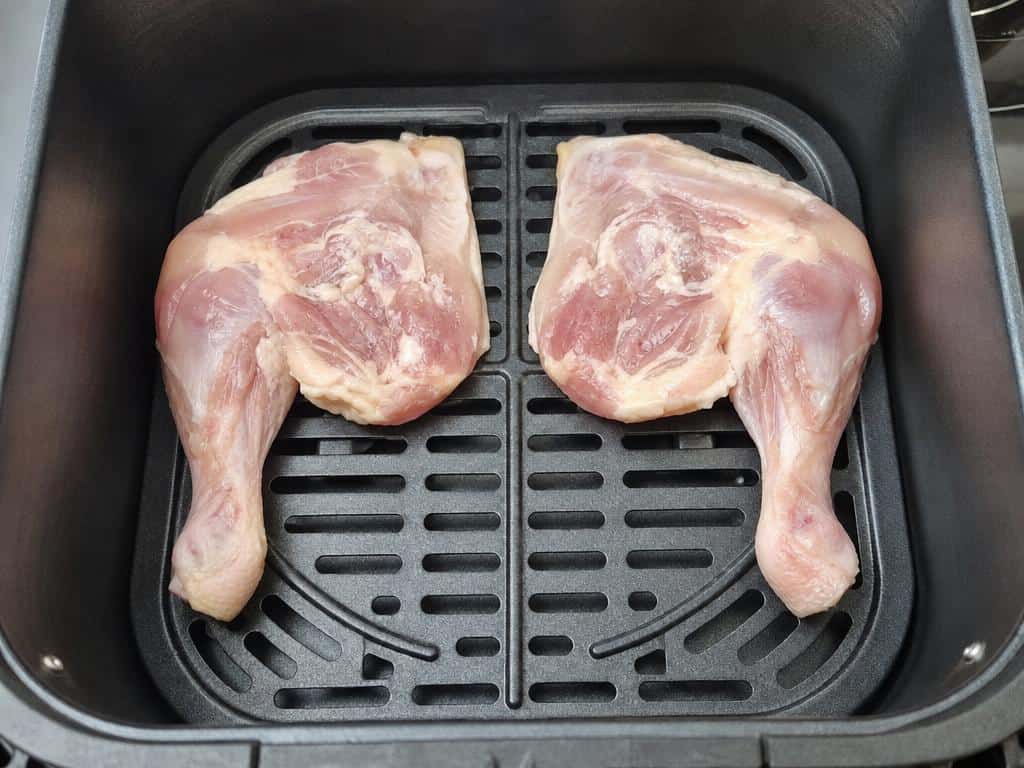 Deux cuisses entières disposées sans chevauchement dans un panier, peau vers le bas.