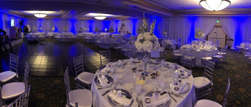 A banquet room with blue lighting and white tables.