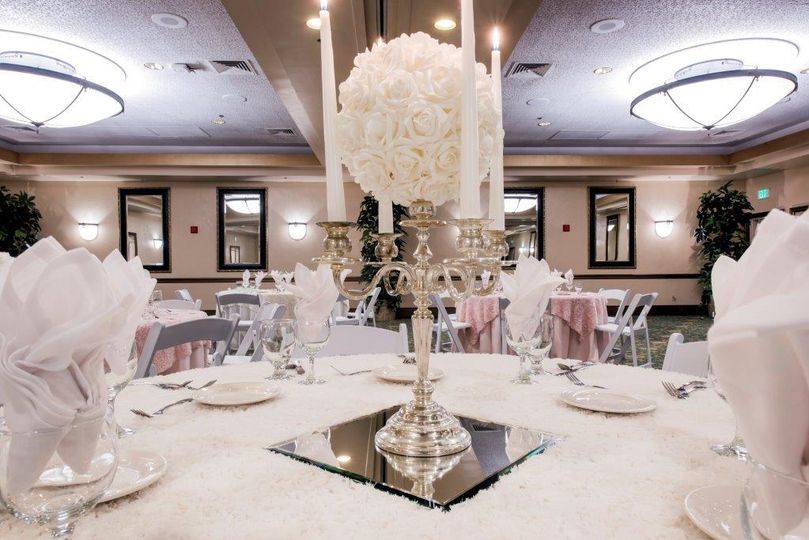 A white table setting with white linens and candles.