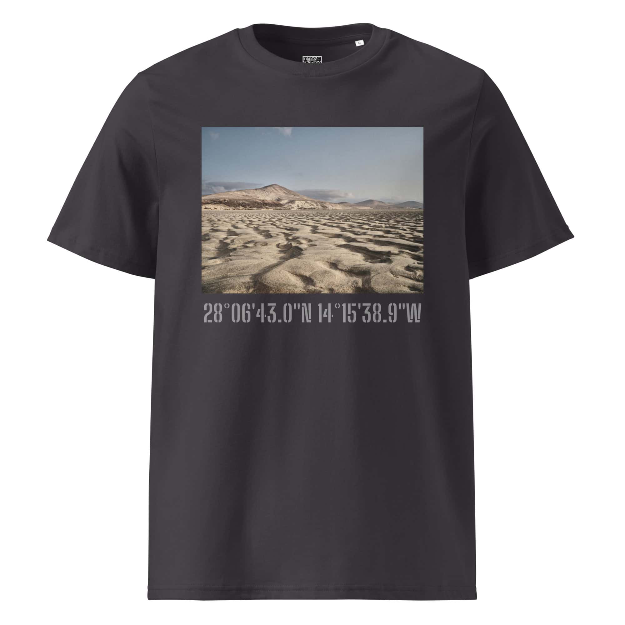 Camiseta unisex Sotavento en color negro con una fotografía de un paisaje desértico que muestra dunas y montañas, capturada por Volcanica Productions. Debajo de la imagen, las coordenadas 28°0643.0N 14°1538.9W están impresas en blanco, exhibiendo los impresionantes Paisajes Canarios con detalle exquisito.