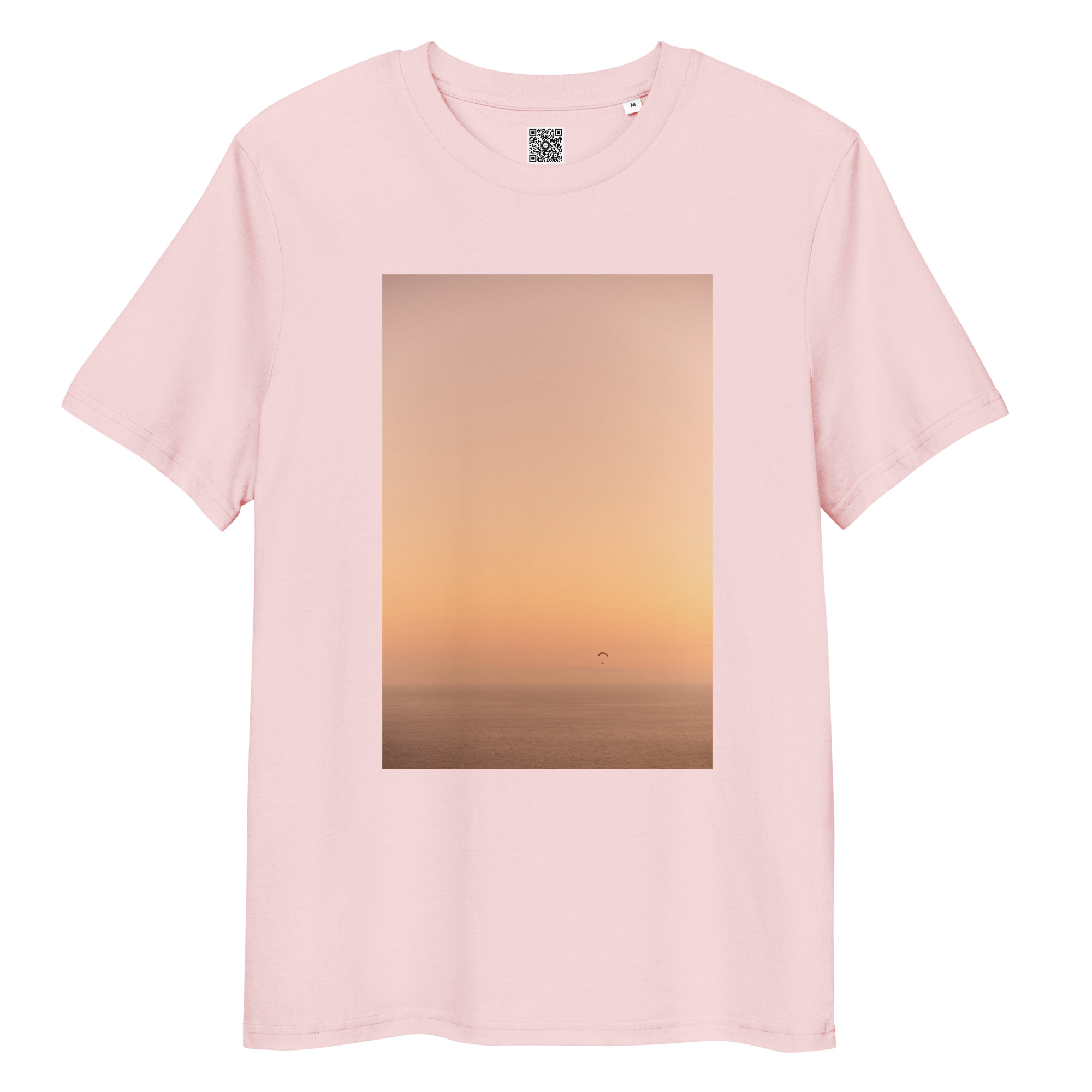 La camiseta unisex Parapente al Atardecer en color rosa presenta un impresionante gráfico de atardecer naranja sobre un mar tranquilo, con una pequeña figura recortada disfrutando del parapente en la distancia.