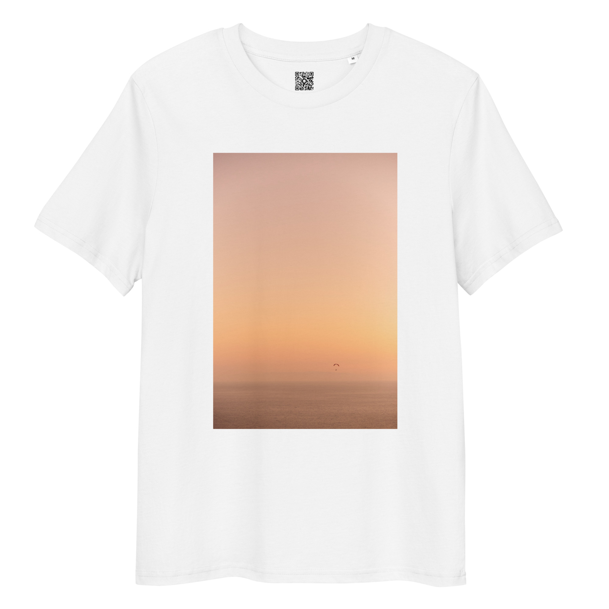 Camiseta unisex Parapente al Atardecer: una camiseta blanca con un estampado rectangular que presenta un atardecer anaranjado sobre el océano, destacando un parapente distante y creando una escena serena y minimalista.