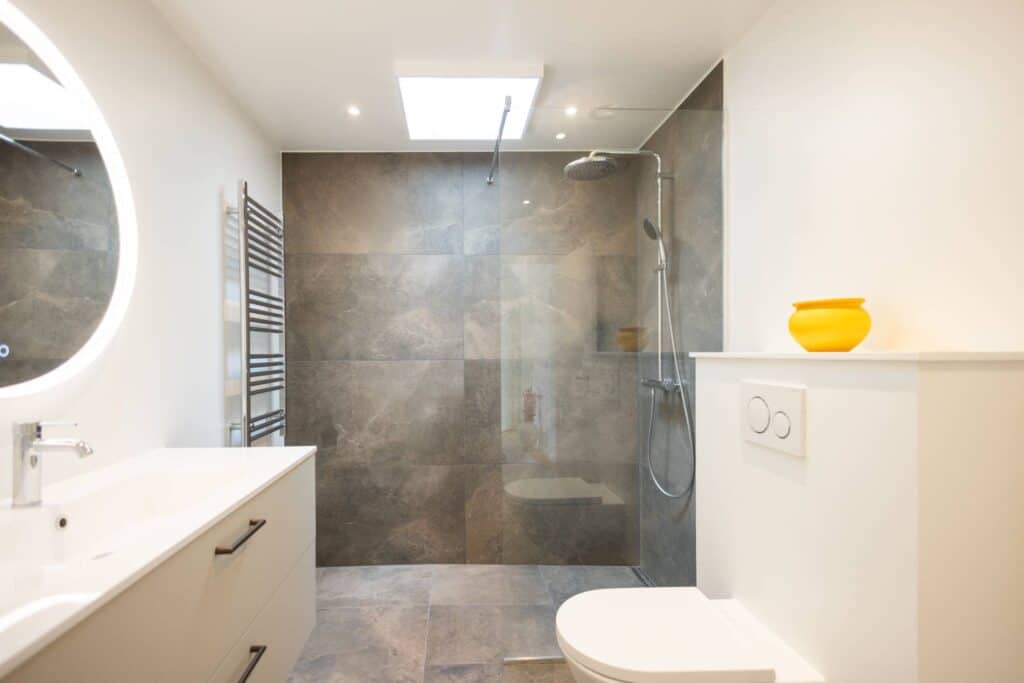 Rummelig walk-in bruser i naturstens-look – totalentreprise badeværelse ved SUN Service