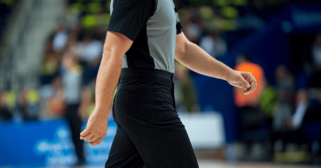 Referee officiating a basketball game during youth sports event.