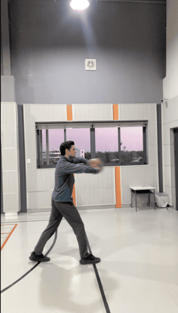 Man practicing basketball passing indoors for youth sports training.