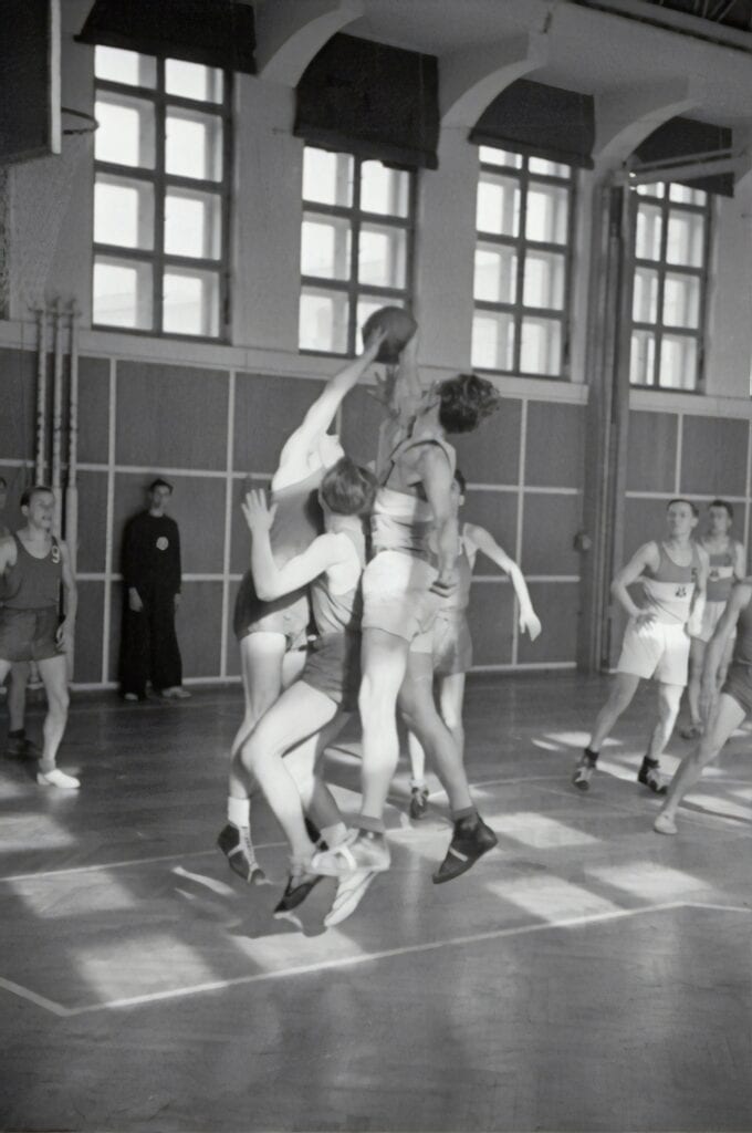 Young athletes practicing basketball drills in gymnasium for youth sports development.