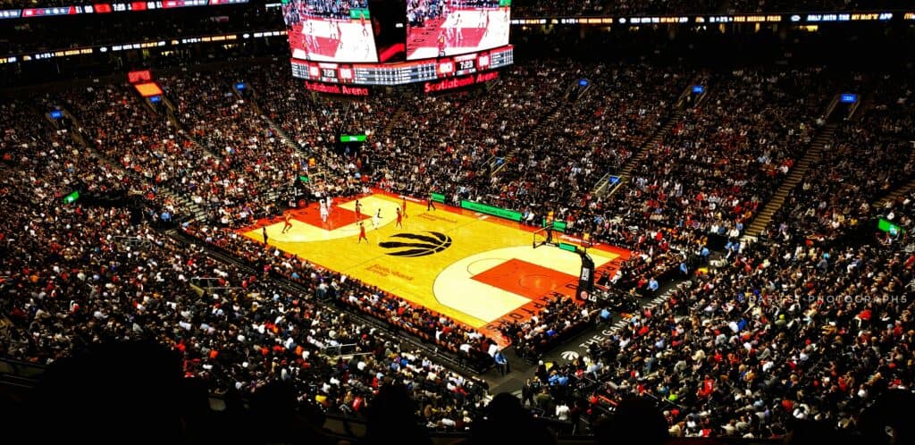 Crowd watching a basketball game at a packed arena.