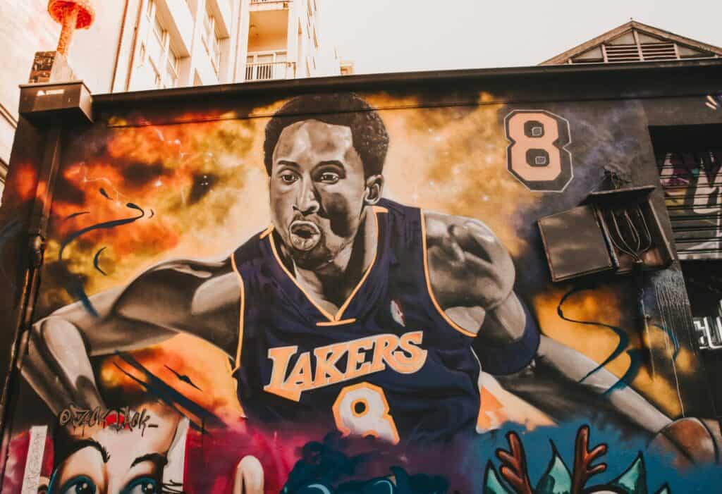 Colorful graffiti mural of a Lakers basketball player in action.