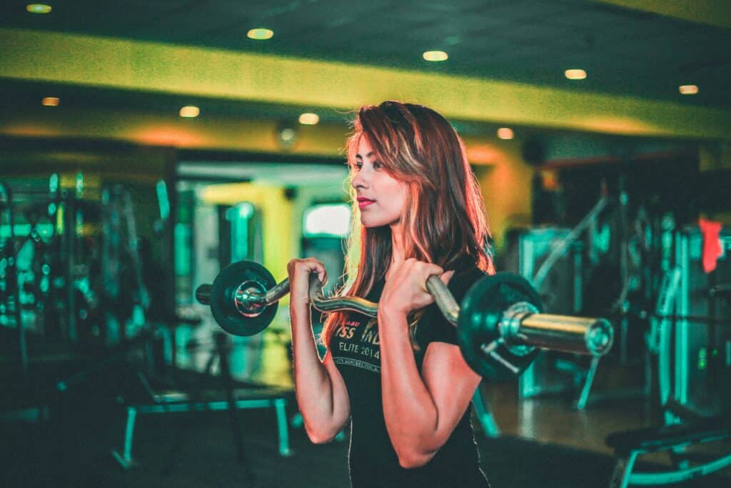 Young woman lifting weights in a gym for fitness and strength training.