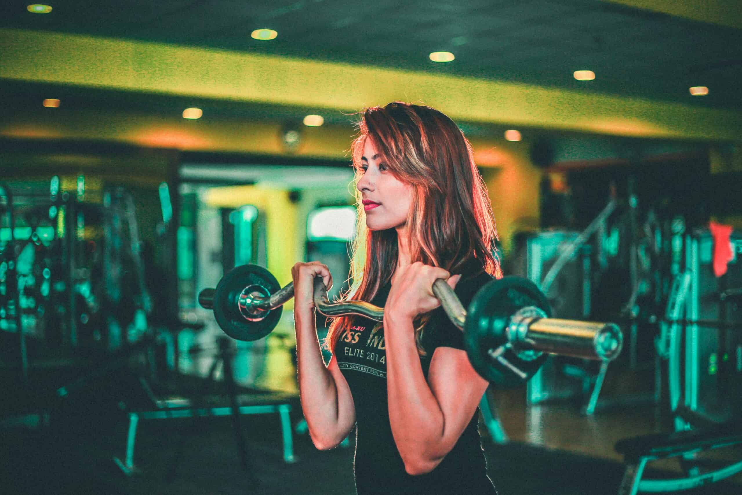 Young woman lifting weights in a gym for fitness and strength training.