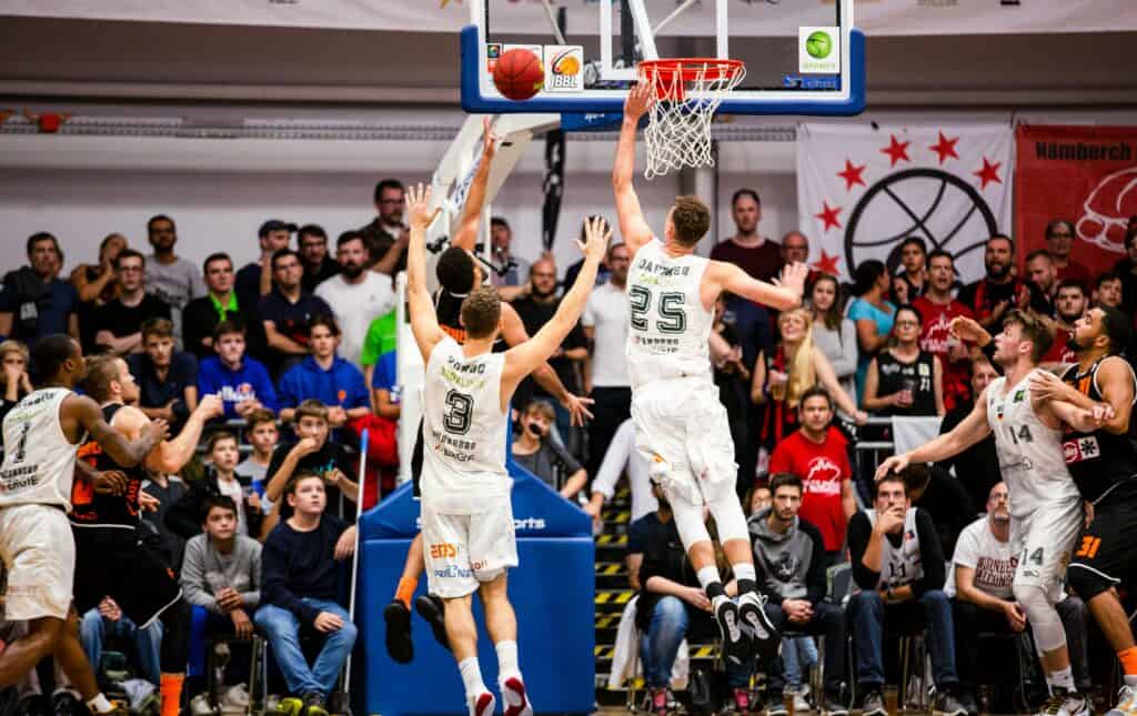 Young basketball players competing in a game with an audience watching.