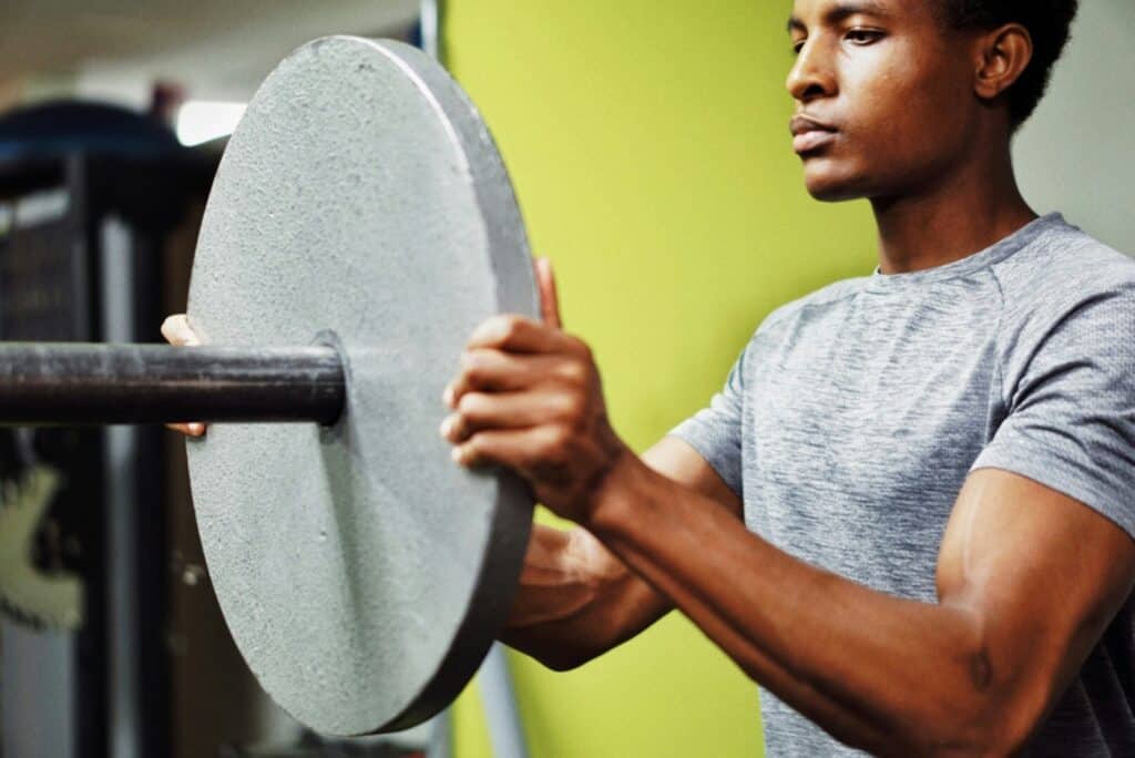 Young man lifting weights for strength and fitness training.