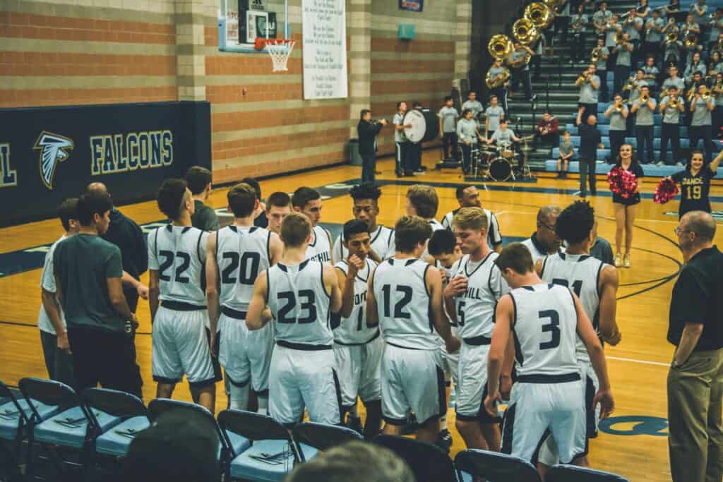 Youth basketball team huddle during timeout at gym.