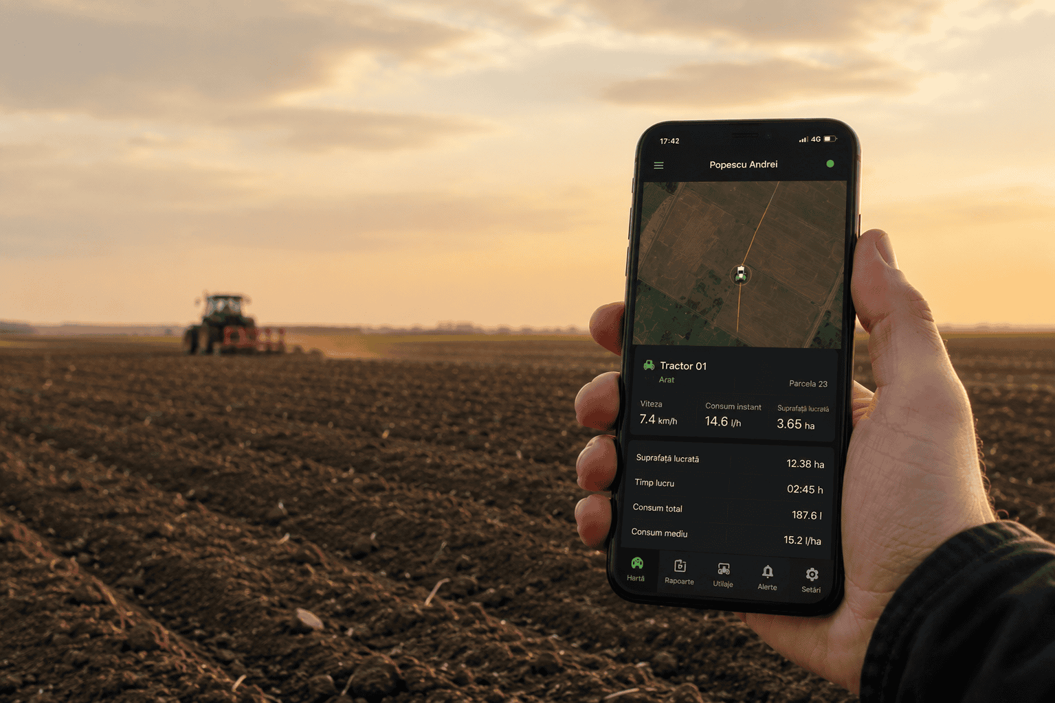 Fermier monitorizând un tractor cu ajutorul unei aplicații mobile, pe câmp, la apus.