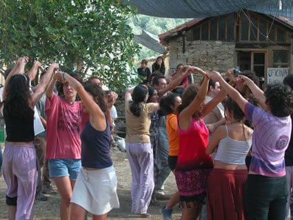 People dancing in a circle at Lakabe Ecovillage, enjoying community and sustainability.
