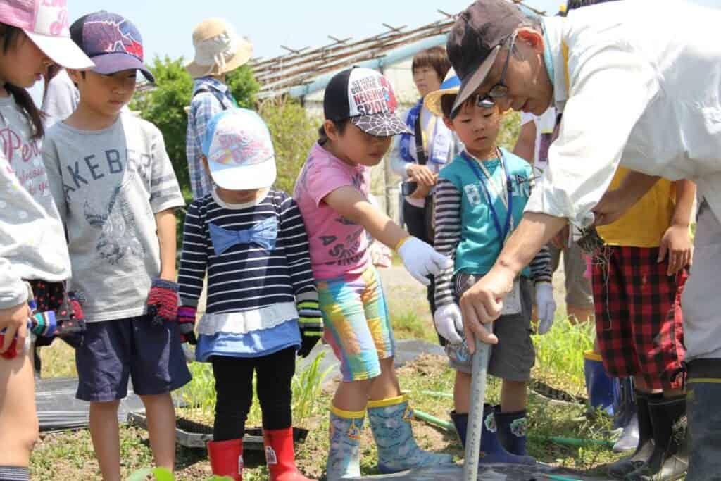 Children participating in outdoor gardening activity at Ecovillage Network event.