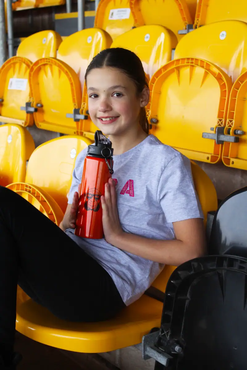 Young girl with water bottle at stadium.