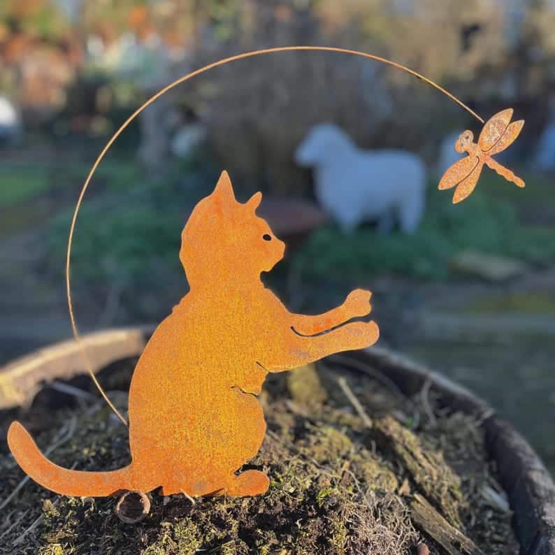 rusted metal cat sculpture with dragonfly