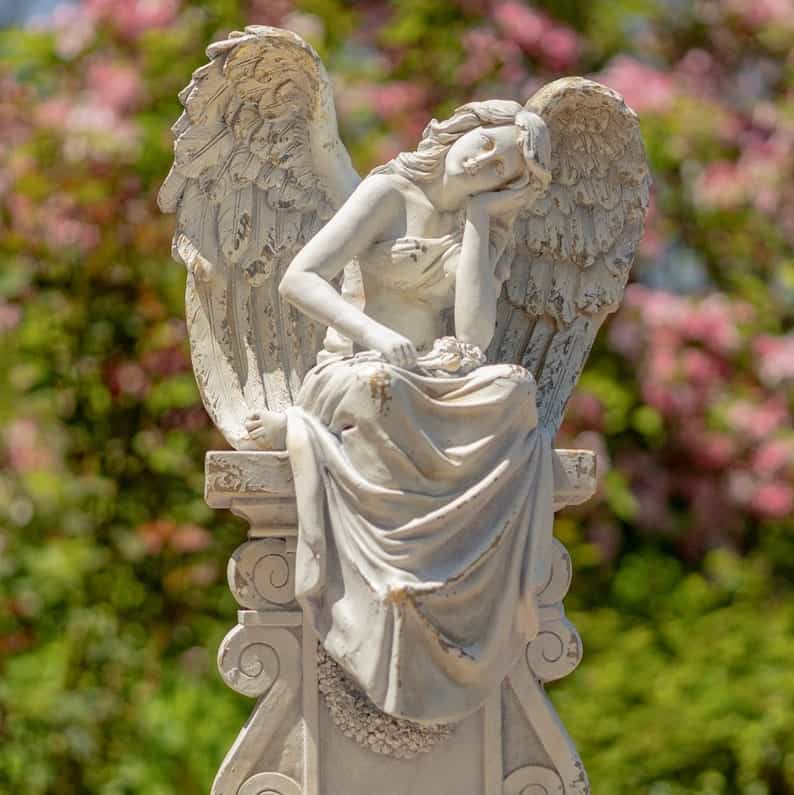 white angel statue sitting on pillar