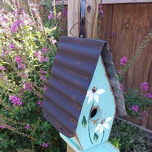 A Framed Bird House with Hand-Painted Flowers and Metal Roof